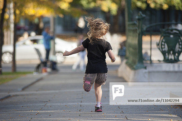 Little girl running on sidewalk