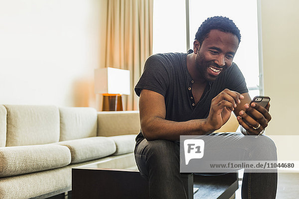 Black man using cell phone in living room