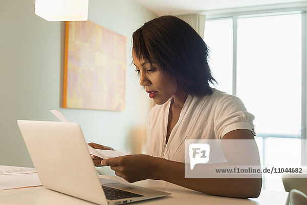 Afroamerikanische Frau bezahlt Rechnungen am Laptop