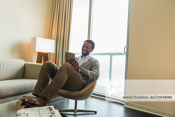 Black man using digital tablet in living room