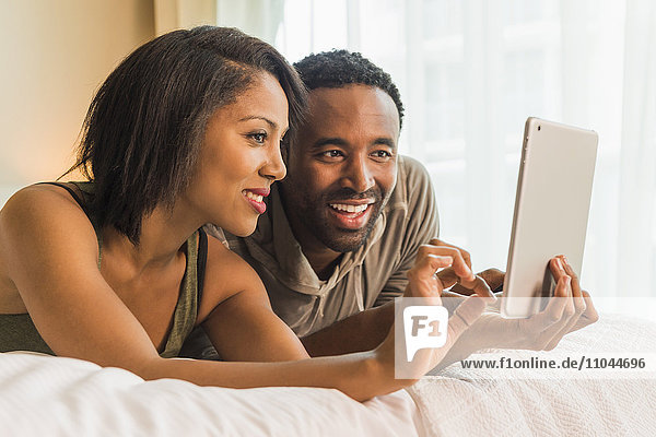 Ehepaar benutzt digitales Tablet auf dem Bett