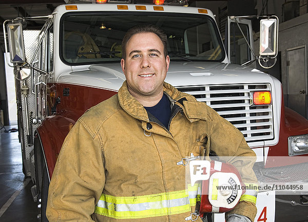 Kaukasischer Feuerwehrmann lächelt in der Nähe des Feuerwehrautos