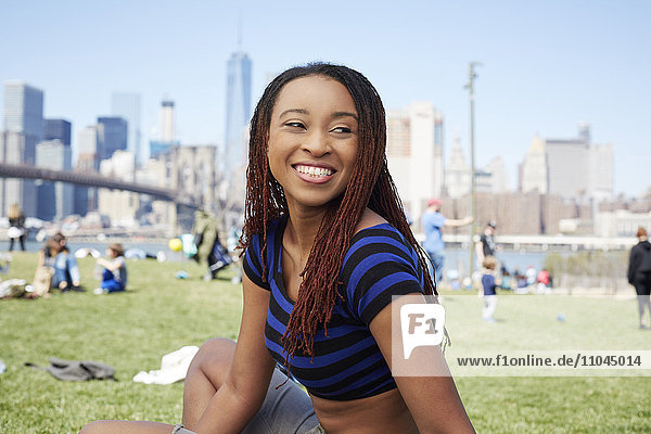Smiling Black woman sitting in grass at waterfront