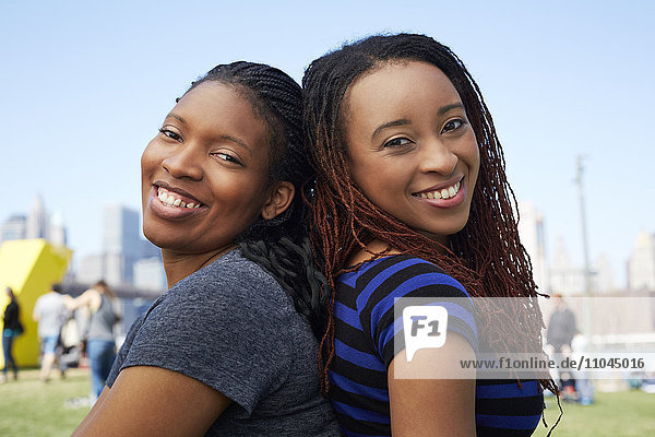 Lächelnde schwarze Frauen sitzen Rücken an Rücken