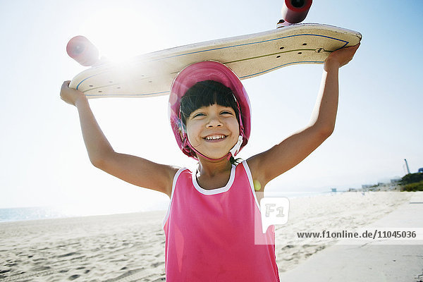 Mixed race girl holding skateboard at beach