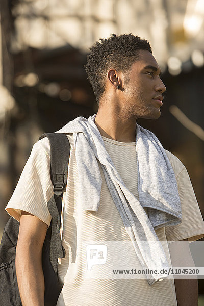 Mixed Race man with backpack and shirt draped over shoulders