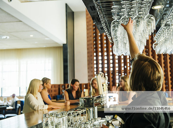 Kaukasischer Barkeeper greift nach einem Weinglas an der Bar