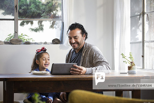 Hispanischer Vater und Tochter benutzen digitales Tablet