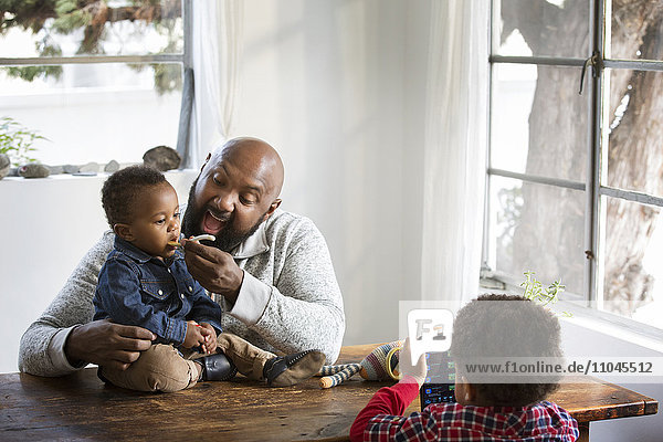 Vater füttert seinen kleinen Sohn am Tisch