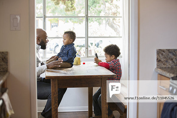 Vater und Kinder sitzen am Tisch