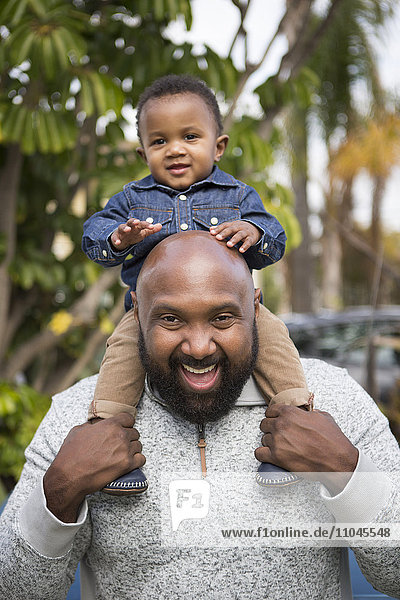 African American father carrying son on shoulders