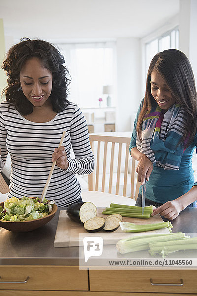 Mother and daughter chopping vegetables for salad