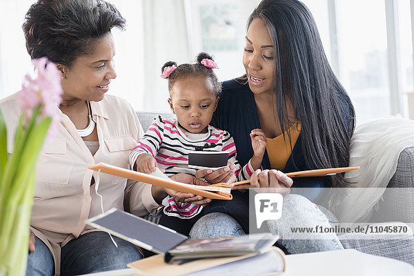 Black multi-generation family looking at photo album
