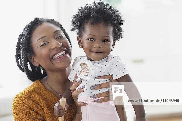 Lächelnde schwarze Mutter hält ihre kleine Tochter