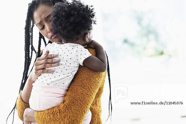Schwarze Frau hält und tröstet ihre kleine Tochter