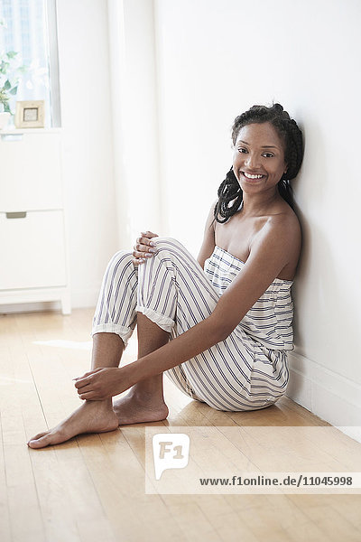 Lächelnde schwarze Frau auf dem Boden sitzend