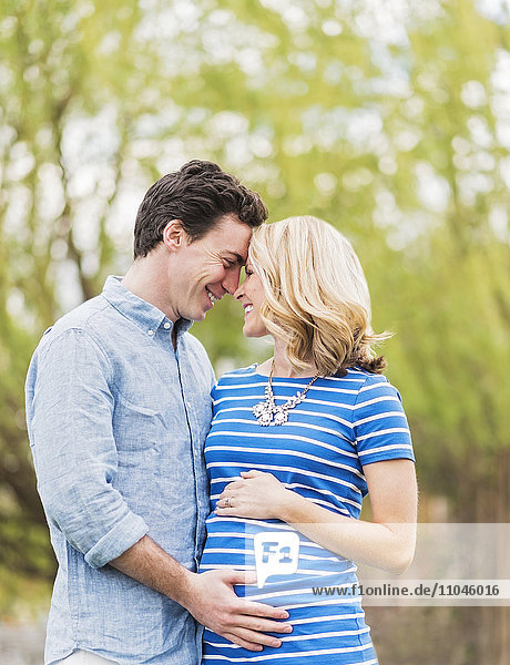 Smiling Caucasian man and expectant mother rubbing noses