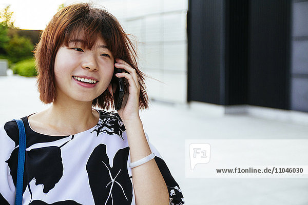 Chinesische Frau  die mit einem Handy telefoniert