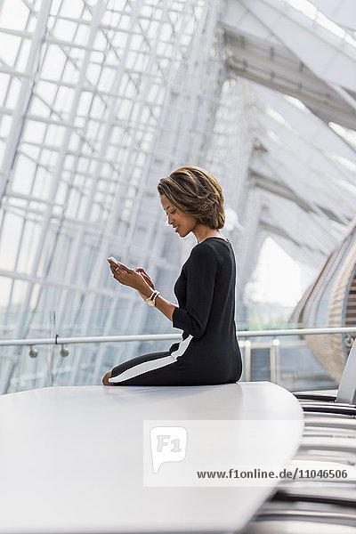 Schwarze Geschäftsfrau benutzt Mobiltelefon in einem Konferenzraum