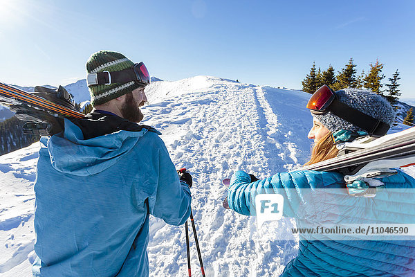 Paar trägt Skier auf verschneitem Berg
