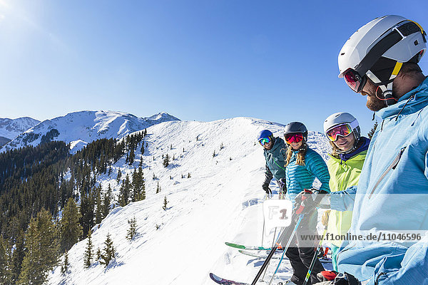 Freunde auf Skiern stehen auf einem verschneiten Berggipfel