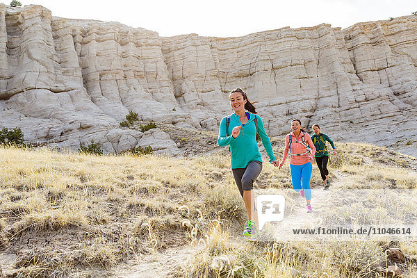 Women running in canyon wearing backpacks