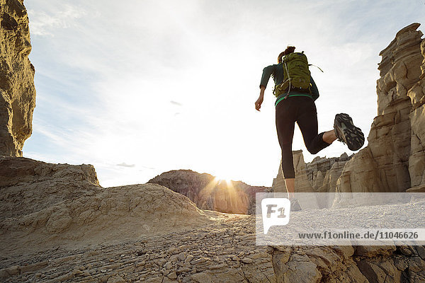 Woman running in canyon wearing backpack