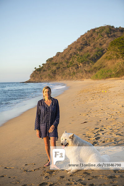 Kaukasische Frau posiert am Strand mit Hund