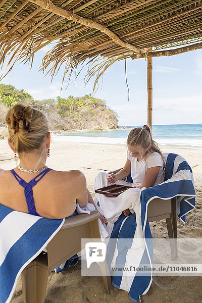Caucasian mother and daughter playing backgammon at beach