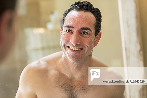 Clean-shaven Hispanic man smiling in mirror