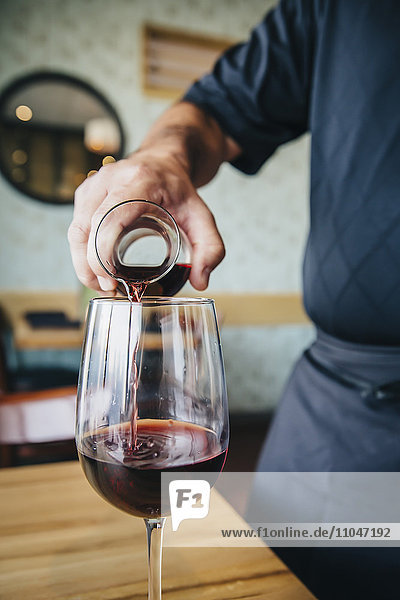 Caucasian waiter pouring wine in cafe