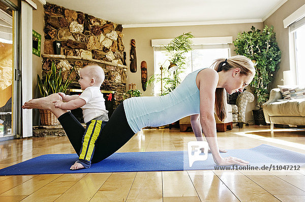 Mother working out on exercise mat with baby on legs