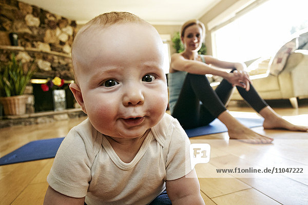 Baby crawling on floor while mother rests from workout