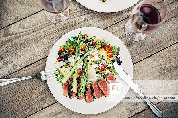 Teller mit Salat und Fleisch mit Weingläsern