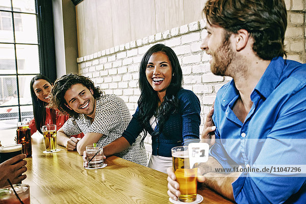 Lächelnde Freunde trinken am Tisch in einer Bar