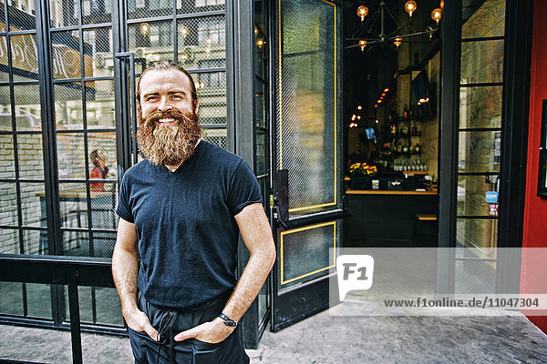 Caucasian man with beard smiling on sidewalk