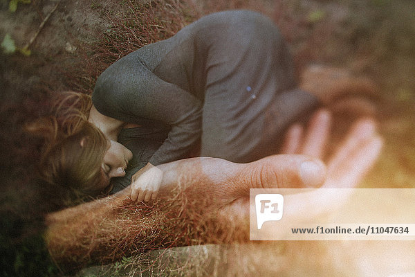 Double exposure of Caucasian woman laying in hand of man