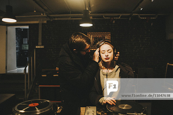 Kaukasischer DJ hält Kopfhörer auf Frau