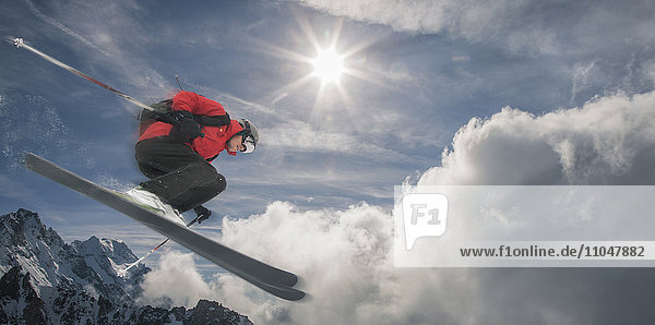 Kaukasischer Skifahrer  der auf einem Berg in die Luft springt