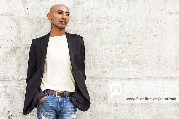 Pensive gay Black man leaning on concrete wall
