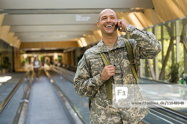 Kaukasischer Soldat  der im Flughafen mit einem Handy telefoniert