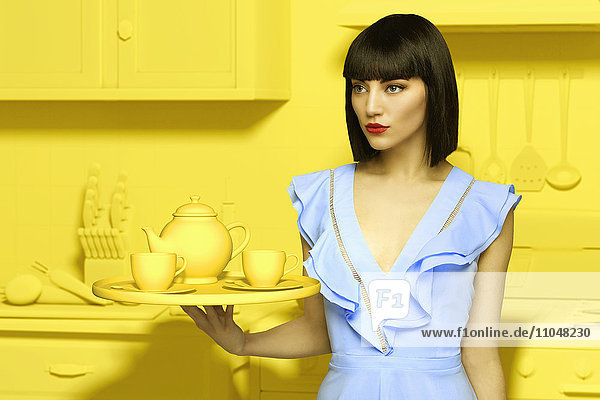 Kaukasische Frau in gelber  altmodischer Küche mit Teeservice
