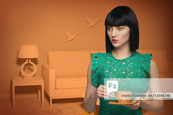 Kaukasische Frau in orangefarbenem  altmodischem Wohnzimmer trinkt Kaffee