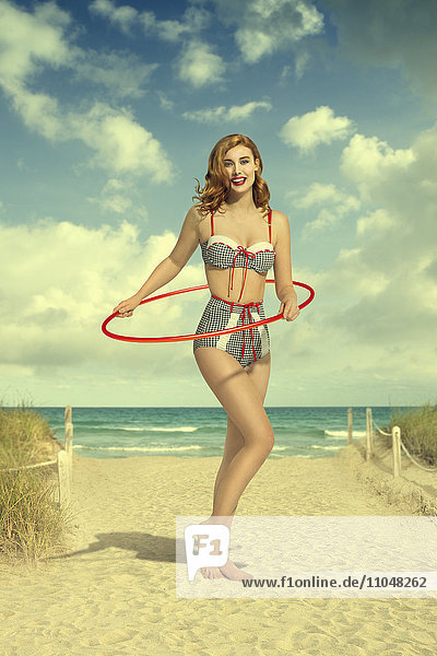 Kaukasische Frau im Bikini hält Plastikreifen am Strand
