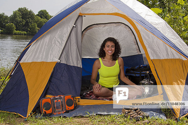 Hispanische Frau lächelnd im Campingzelt am See