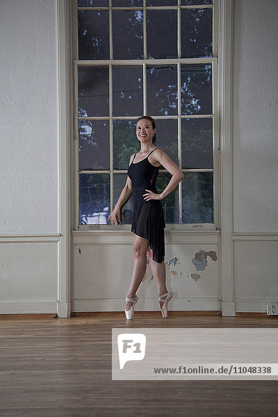 Asiatische Ballerina posiert am Fenster im Studio