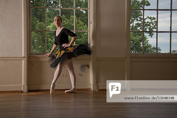 Kaukasische Ballerina posiert am Fenster im Studio