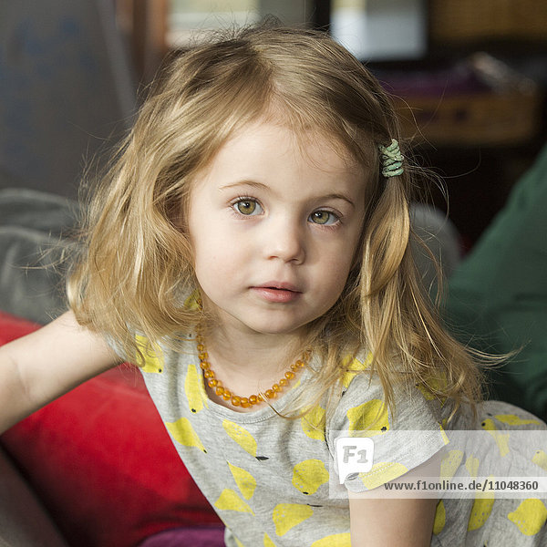 Caucasian preschooler girl sitting on sofa