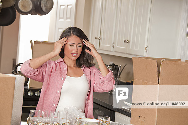 Frustriert lächelnde Spanierin in der Küche mit Kartons