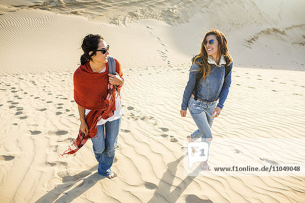 Gemischtrassige Frauen gehen auf Sanddünen